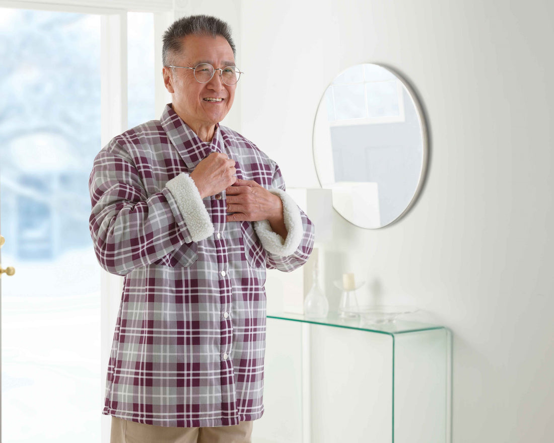 Older man standing in home front hall doing up jacket.