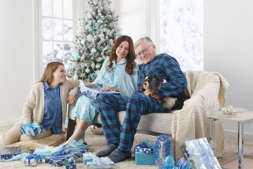 A woman unwraps christmas presents with her parents.