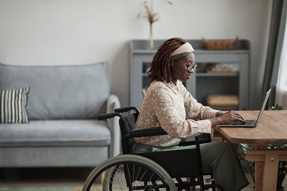 a woman in a wheelchair using a laptop at a desk