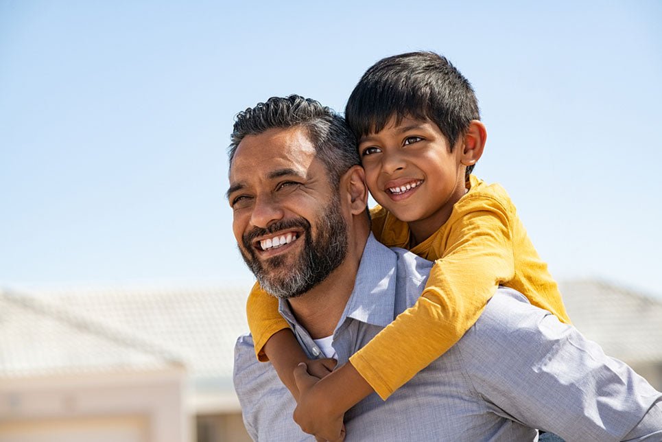 smiling father carrying son on back