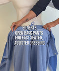 Model demonstrates a blue open back pants for easy seated, assisted dressing